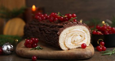 Lezzetli Noel kütüğü (geleneksel Noel pastası) ahşap masa üzerinde kırmızı frenk üzümü, yakın plan