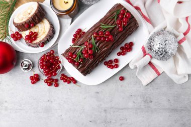 Lezzetli Noel kütüğü (geleneksel Noel pastası) kırmızı frenk üzümü ve gri desenli masa, düz yatak. Metin için boşluk