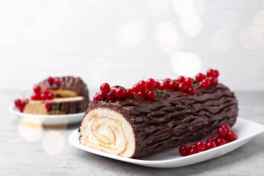 Lezzetli Noel kütüğü (geleneksel Noel pastası) gri desenli masa üzerinde kırmızı frenk üzümü, yakın plan