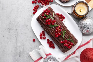 Lezzetli Noel kütüğü (geleneksel Noel pastası) kırmızı frenk üzümü ve gri desenli masa, düz yatak. Metin için boşluk