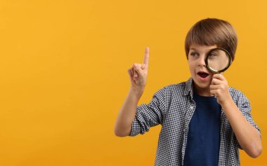 Sarı arka planda büyüteç olan küçük bir çocuk. Metin için boşluk