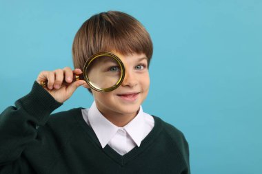 Açık mavi arka planda büyüteç takan küçük bir çocuk. Metin için boşluk
