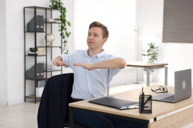 Genç işadamı kollarını uzatıp, masada oturuyor.