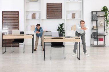 Erkek ve kadın ofiste esneme egzersizi yapıyorlar.