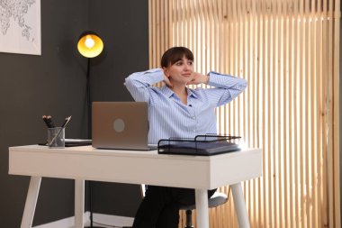 Genç iş kadını ofiste sırtını esnetiyor.