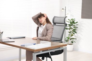 Genç iş kadını ofiste boynunu uzatıyor.