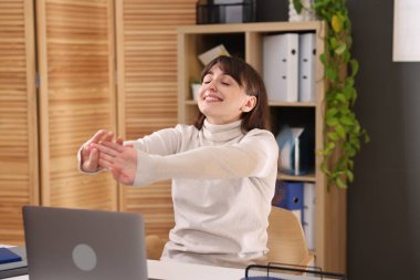 Ofiste kollarını açan genç iş kadını.