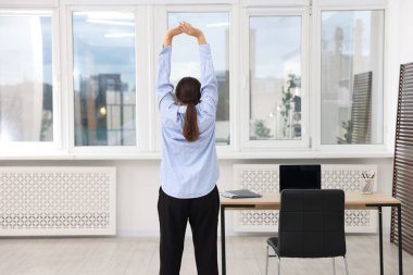 Genç iş kadını gerinme egzersizi yapıyor.