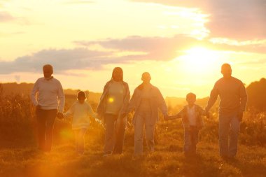 Mutlu aile gün batımında el ele tutuşuyor.