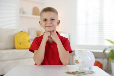 Cep harçlığı ve kumbarası olan küçük bir çocuk.