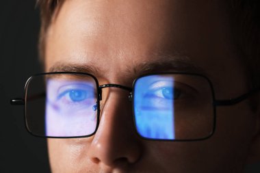 Karanlık arka planda yansıması olan gözlüklü bir adam, yakın plan.