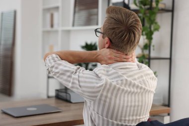 Genç işadamı masanın arkasında boynunu uzatıyor.