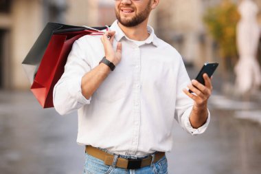 Farklı alışveriş çantaları ve açık havada telefonu olan adam, yakın plan.