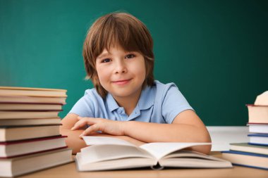 Okula dönelim. Çocuk masa başında karatahtaya karşı çalışıyor.