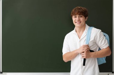 Okula dönelim. Sırt çantalı öğrenci yazı tahtasının yanında, metin için boşluk