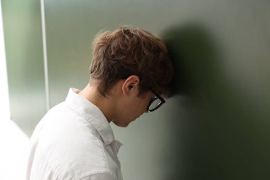 Okula dönelim. Kapalı alanda tahtaya yakın üzgün bir çocuk.