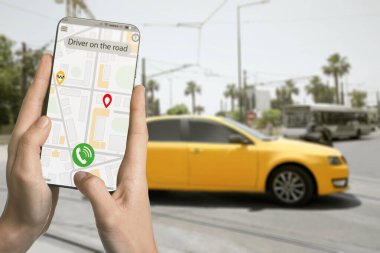 Şehir caddesinde taksi çağırmak için cep telefonu uygulaması kullanan bir adam.