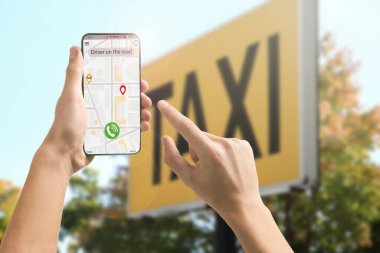 Şehir caddesinde taksi çağırmak için cep telefonu uygulaması kullanan bir adam.
