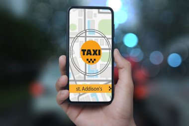 Şehir caddesinde taksi çağırmak için cep telefonu uygulaması kullanan bir adam.