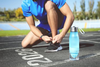 Yeni yıl. Stadyumda 2026 numaraya yakın ayakkabı bağlayan adam, yakın plan.