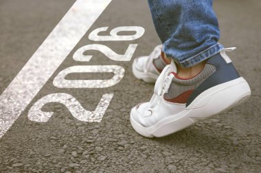 Yeni yıl. Asfalt üzerinde 2026 numarayla çizgiye doğru yürüyen adam, yaklaş.