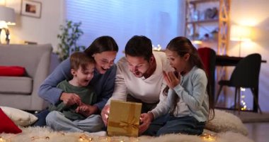 Mutlu bir aile sihirli Noel hediyesiyle yerde süslenmiş bir odada