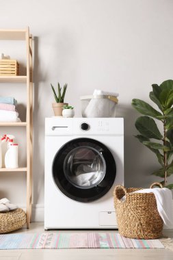 Çamaşır odasında çamaşır, deterjan ve çiçekli çamaşır makinesi. İç tasarım