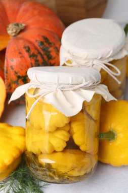 Kavanozlarda turşulu köfte kabakları ve ışık masasında taze sebzeler, yakın plan.