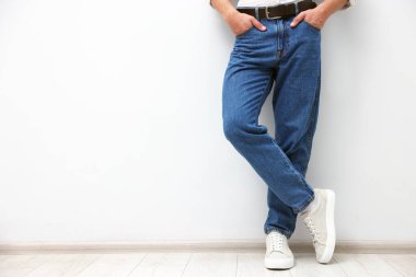 Beyaz duvarın yanında şık kotlu bir adam, yakın plan. Metin için boşluk