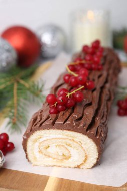 Lezzetli Noel kütüğü (geleneksel Noel pastası) kırmızı frenk üzümü, dekor ve köknar ağacı dalları ile masada, yakın plan