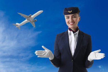 Mavi gökyüzüne karşı üniformalı mutlu hostes.