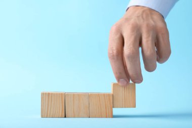 Açık mavi arka planda tahta küpleri olan adam, yakın plan. Metin için boşluk