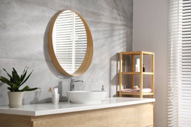 Lavabonun üzerinde yuvarlak aynası olan şık bir banyo. İç tasarım