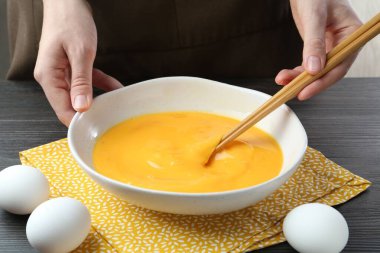 Koyu ahşap masada yumurta çırpan kadın, yakın plan.