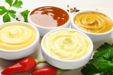 Farklı lezzetli soslar, maydanoz, biber ve beyaz ahşap masada kırmızı biber, yakın plan.