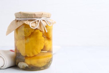 Cam kavanozda köfte kabağı turşusu ve beyaz fayanslı masada havlu, yakın plan. Metin için boşluk