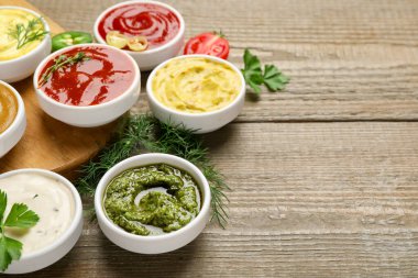 Ahşap masada farklı soslar ve otlar, yakın plan. Metin için boşluk