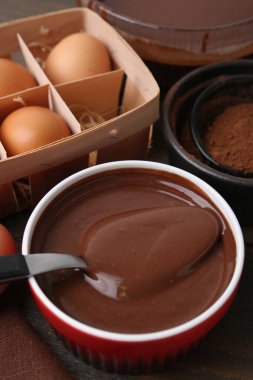 Sıvı çikolata hamuru kasede ve malzemeler ahşap masada, yakın plan.