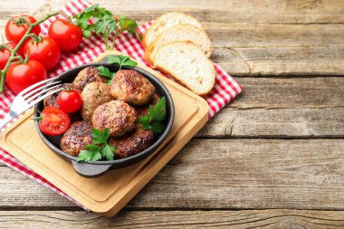 Maydanozlu lezzetli köfteler, tavada domatesler ve ahşap masada çatal, yakın plan. Metin için boşluk