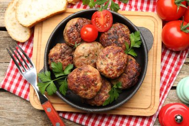 Maydanozlu leziz köfteler, domates ve ekmek ahşap masada servis edilir.