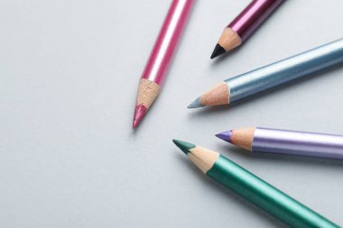 Hafif arka planda renkli göz kalemleri, düz yatış. Metin için boşluk