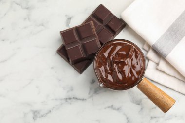 Erimiş çikolata ve parçalar beyaz mermer masada, düz yerde. Metin için boşluk