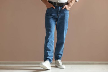 Bej duvarın yanında şık kotlu bir adam, yakın plan.