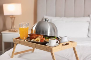 Otel odasında yatakta nefis bir kahvaltı tepsisi.