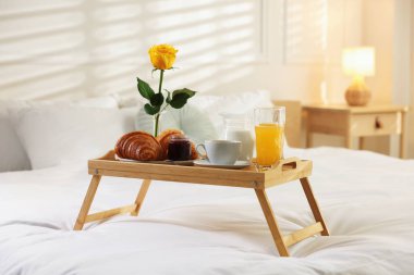 Otel odasında yatakta nefis bir kahvaltı tepsisi.