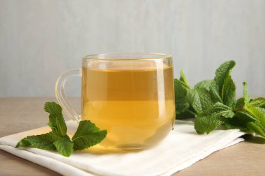 Bir fincan lezzetli çay ve nane, ahşap masada, yakın plan.