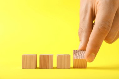 Sarı arka planda tahta küpleri olan adam, yakın plan. Metin için boşluk