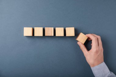 Gri arka planda tahta küpleri olan adam, üst manzara.