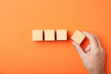 Turuncu arka planda tahta küpleri olan bir adam.