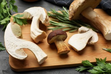 Taze Porcini mantarları ve siyah masada bitkiler, yakın plan.